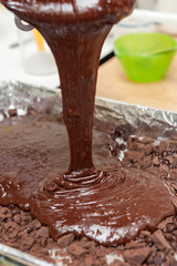 pouring mixture of chocolate eggs and flour preparing for bake b
