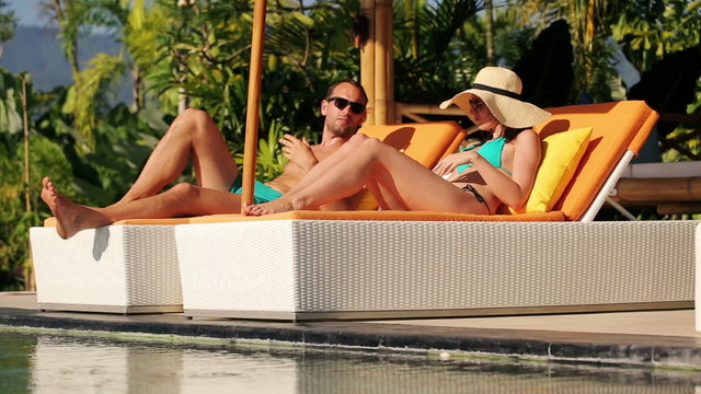 Young couple fighting, arguing on sunbeds by the pool