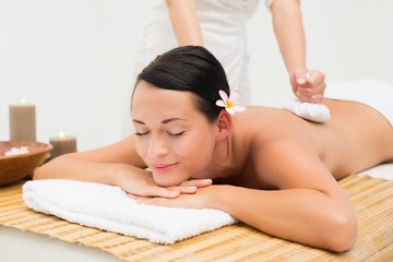 Obraz na płótnie Canvas Peaceful brunette enjoying a herbal compress massage