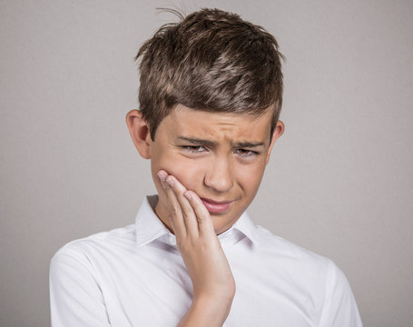Headshot Unhappy boy with toothache on grey wall background 