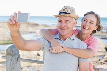 Obraz premium Happy casual couple taking a selfie by the coast