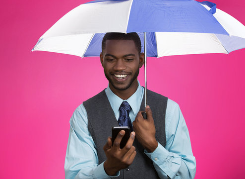 Happy corporate man reading news on phone holding umbrella