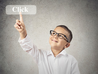 Happy boy pushing on Click button, grey wall background 