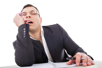 exhausted businessman sleeping at his desk yawning