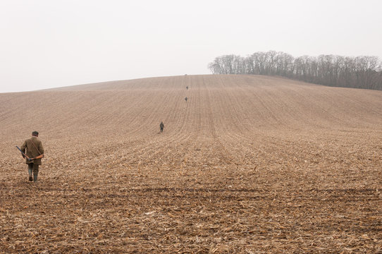 Gamekeepers walk over field in november fog.