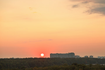 Fototapeta na wymiar low red sun above horizon during sunrise over city