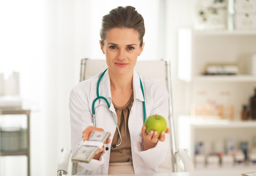 Doctor Woman Showing Apple And Pack Of Money