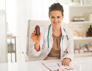 Smiling doctor woman showing medicine bottle