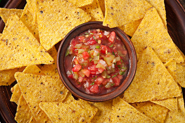 Mexican nacho chips and salsa dip in bowl on wooden background - obrazy, fototapety, plakaty