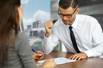 Couple Signing Salesman Contract. Car Showroom