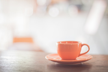 Mini orange coffee cup on wooden table