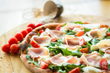 Pizza with cherry tomatoes, prosciutto and ruccola