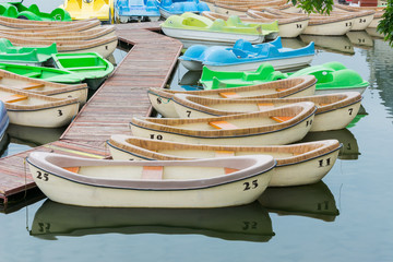 Fototapeta premium Pleasure rowing boats and pedalos tied up on a lake