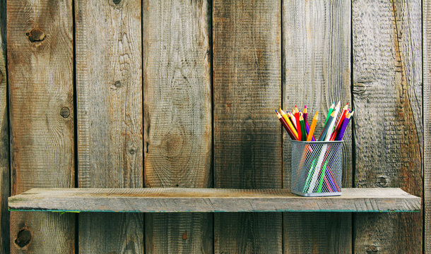 Pencils on a wooden shelf.