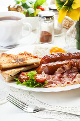 Full English breakfast with bacon, sausage, fried egg and baked