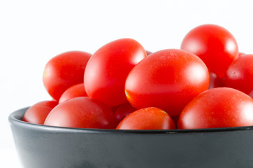 cherry tomatoes in a black bowl isolated on white