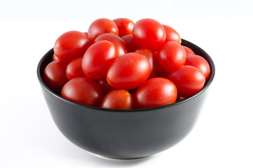 cherry tomatoes in a black bowl isolated on white