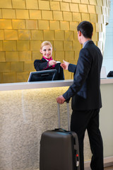 Rezeptionistin checkt Mann bei Anreise im Hotel ein