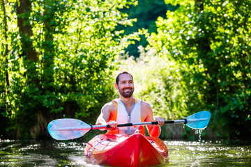 Mann fährt im Kajak auf Wald Fluss 