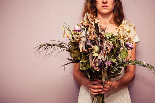 Young Woman Holding Bouquet Of Dead Flowers