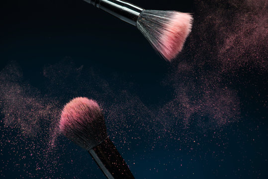 Fototapeta Professional black make-up brush with pink powder in motion isol