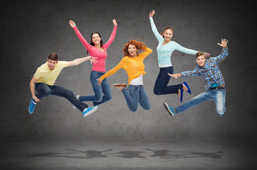 group of smiling teenagers jumping in air