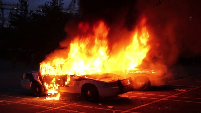 Police cruisers burning with electrical explosion during riot