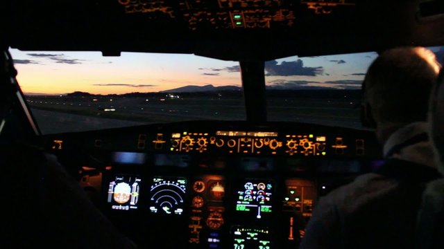 Pink sunset viewed from airplane cockpit with dashboard lights