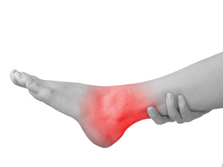 Acute pain in ankle. Woman holding hand to spot of ankle-aches.