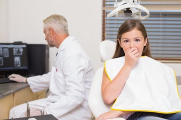 Terrified little girl looking at camera in dentists chair