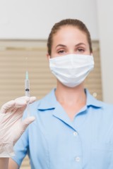 Dental assistant holding injection looking at camera