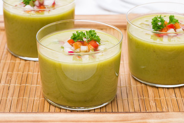green soup with fresh vegetables on a wooden tray, close-up