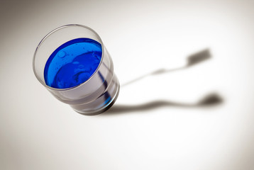 Blaues Wasser im Glas mit Zahnbürsten Schatten
