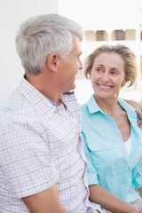 Happy mature couple sitting on bench in the city