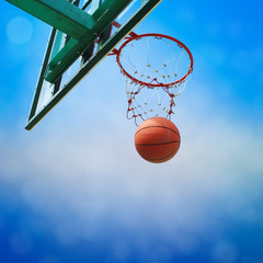 basketball drop into the orange metal goal and white net.