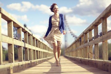 happy girl dress runs over the bridge - obrazy, fototapety, plakaty
