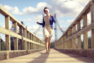 happy girl dress runs over the bridge