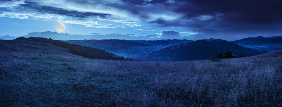 valley in mountains  on hillside under sky with clouds at night