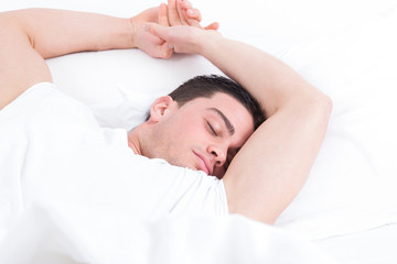 Fototapeta na wymiar man lying in bed and having sweet dreams while sleeping