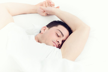 Photo of handsome man sleeping on soft white pillow
