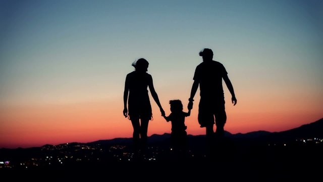 Family walking at sunset.  Silhouette of family.