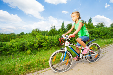 Obraz premium Small cute girl riding children bike on road