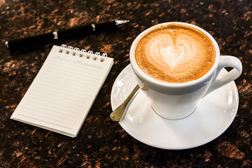 Open a blank white notebook, pen and cup of coffee on marble des