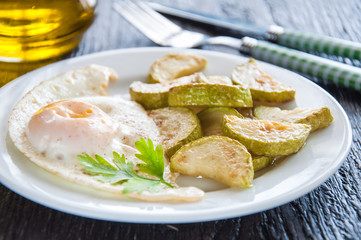 fried eggs and chopped zucchini with parsley on the plate