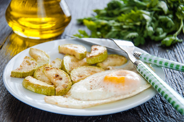 fried eggs and chopped zucchini with parsley on the plate