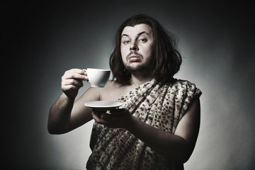 Savage man in skin of beast drink tea or coffee - obrazy, fototapety, plakaty