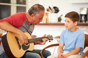 Grandfather Teaching Grandson To Play Guitar