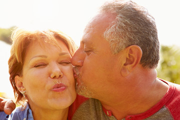 Affectionate Senior Couple Kissing In Garden