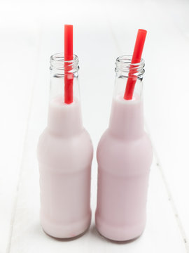 two bottles of pink milk with straws