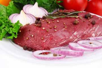 Raw beef meat with vegetables on plate close up